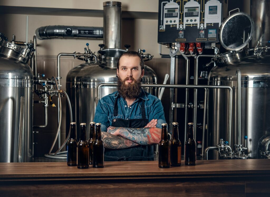 A man manufacturer presenting beer in the microbrewery.